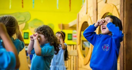Group of children using their hands like goggles over their eyes