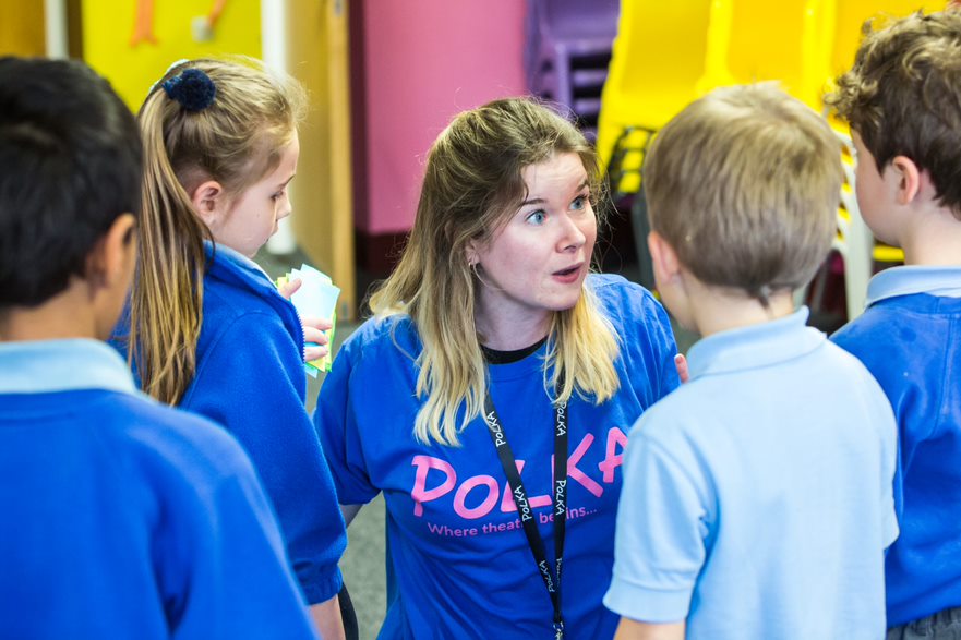 Female workshop leader in Polka t-shirt surrounded by children
