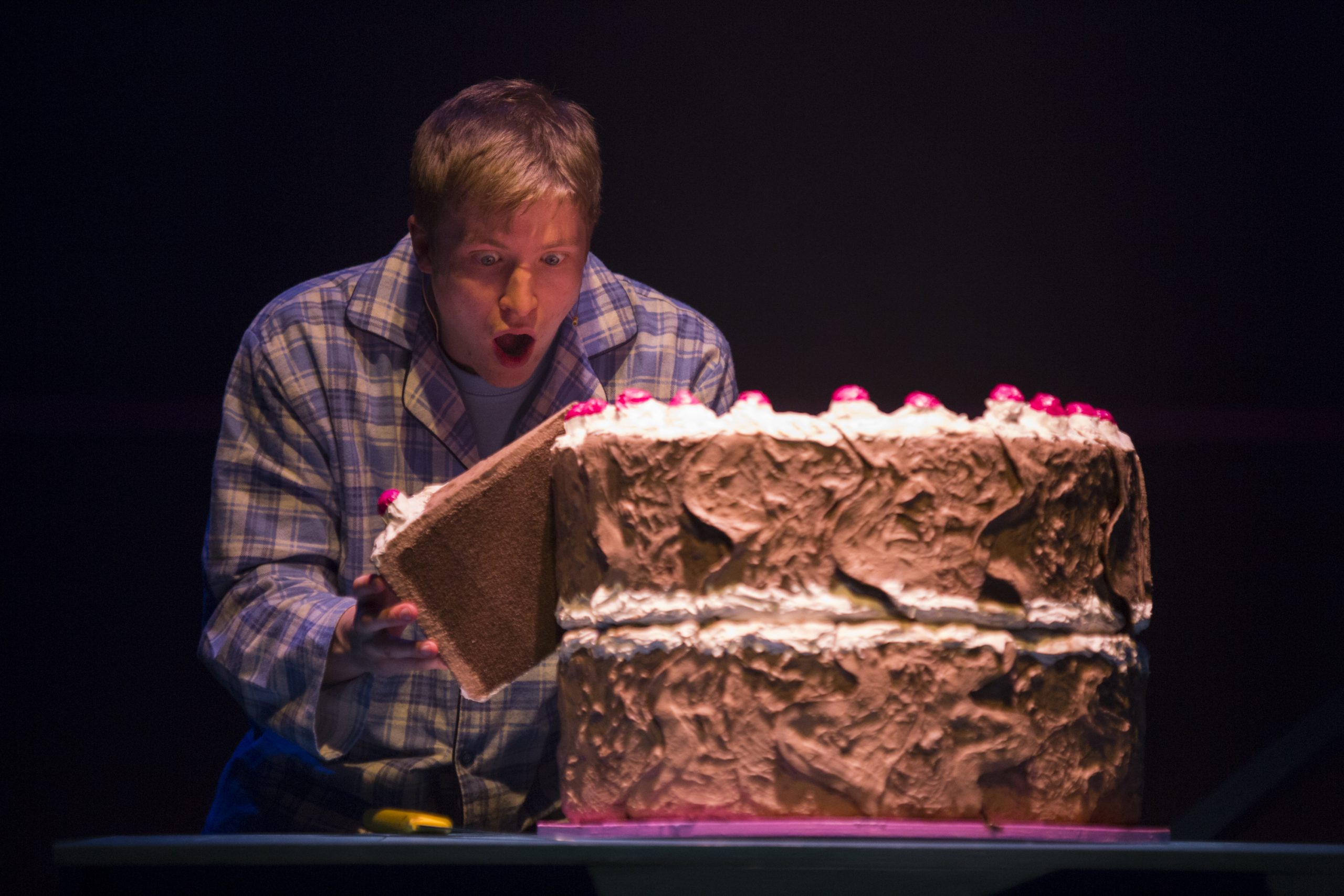 A boy with a giant chocolate cake in Polka Theatre's production of Michael Rosen's Chocolate Cake
