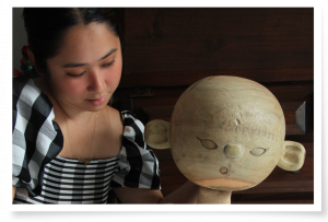 Mikayla Teodoro (dark hair tied back and a black and white checked top) operates a puppet