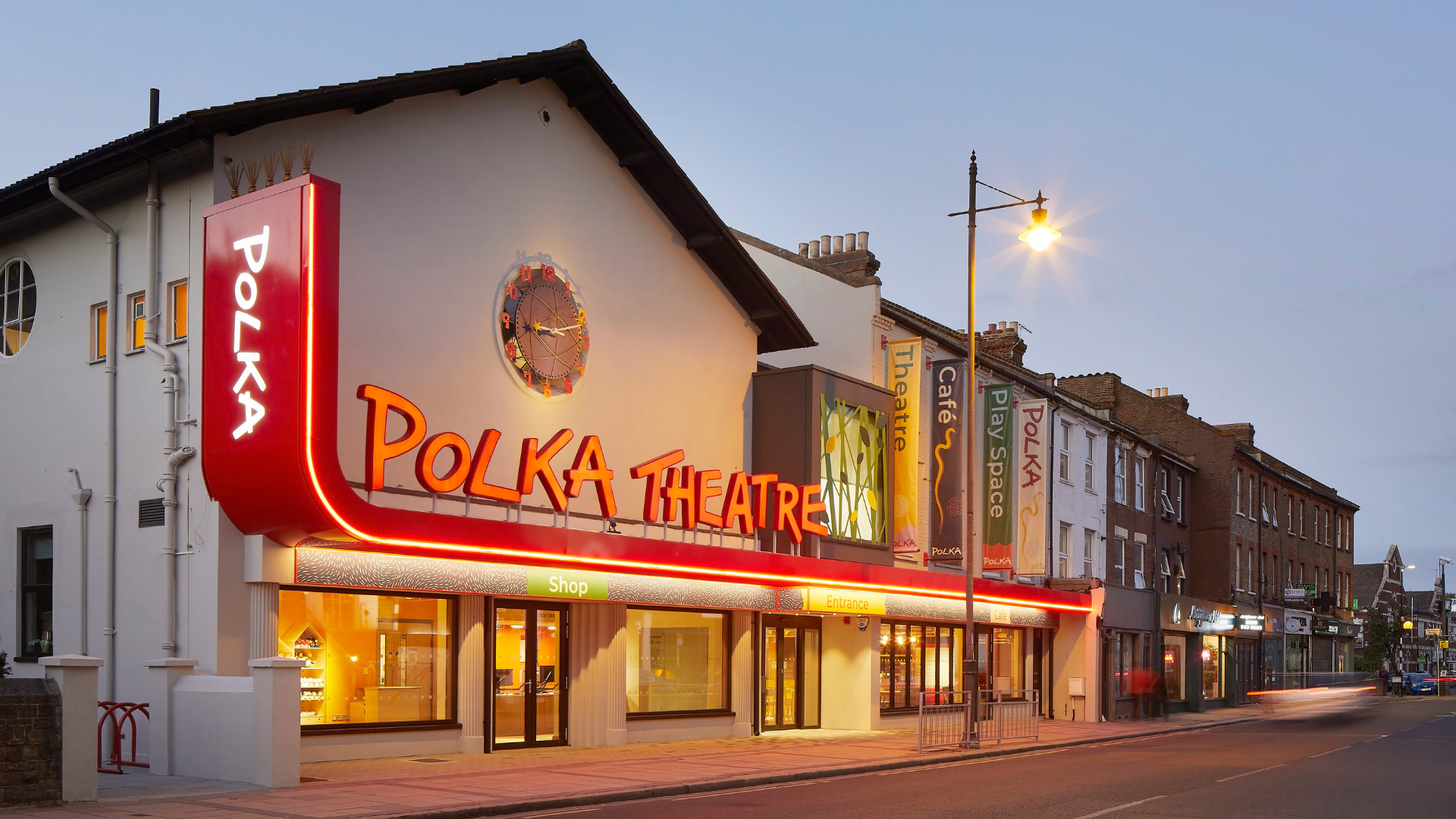 An outside shot of the Polka Theatre at night lit up.
