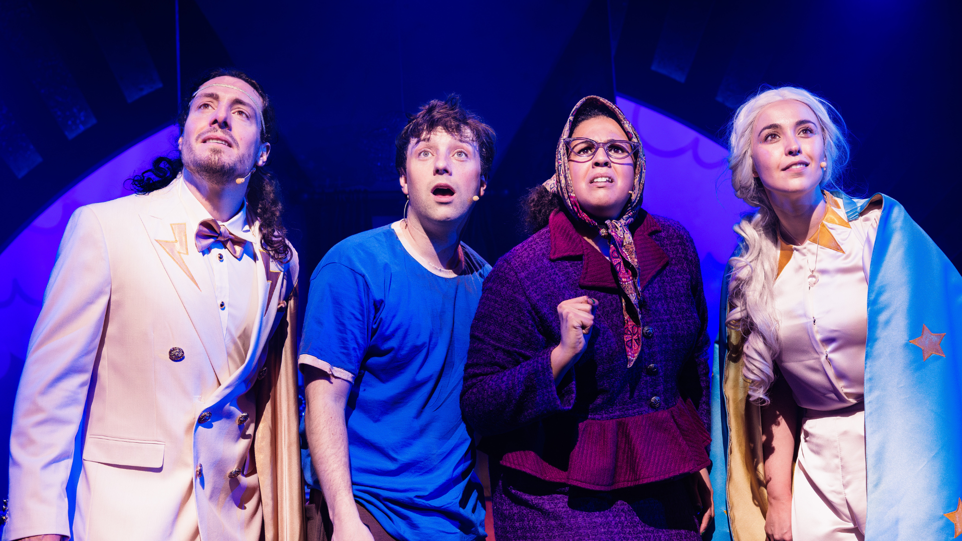 A group of adults performing on stage looking onwards in the same direction.