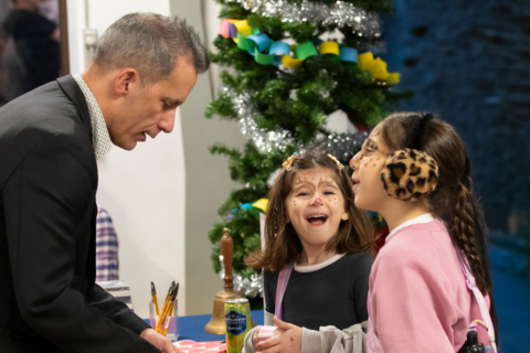 A couple of young children having their faces painted as reindeers at Christmas time.