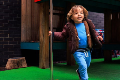 A toddler playing outside in the Polka play area.