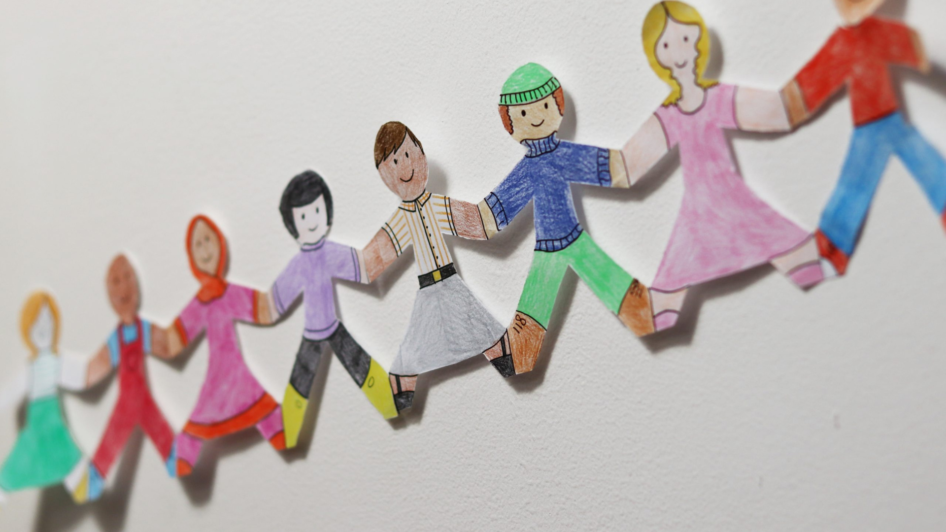 A paper chain of people holding hands, coloured in with pencil crayon.