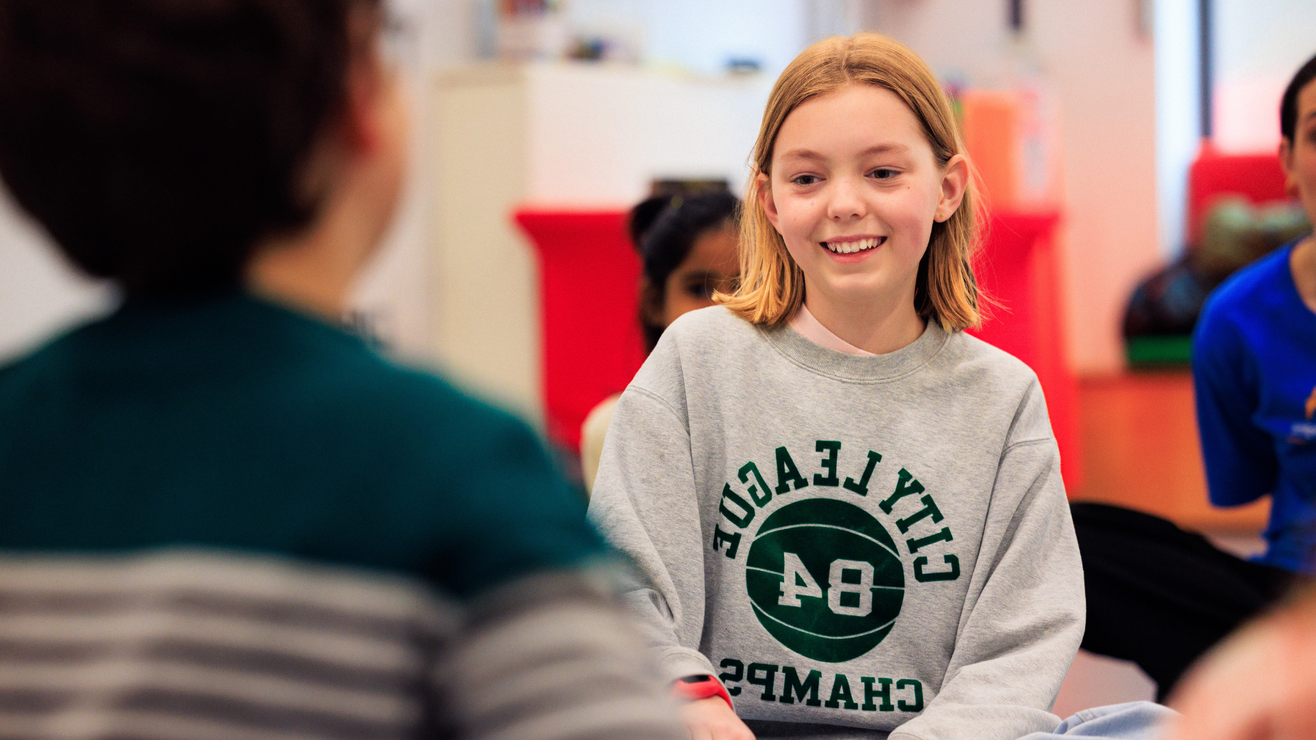 A young person sat on the floor in conversation with other young people.